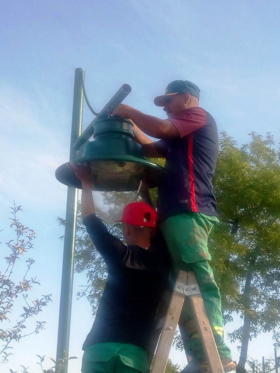 Trabajadores municipales de Merlo reparando una de las luces de la plaza.